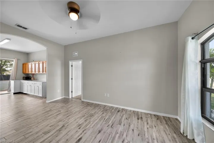 Unfurnished living room featuring light wood-style floors, a ceiling fan, arched walkways, and baseboards