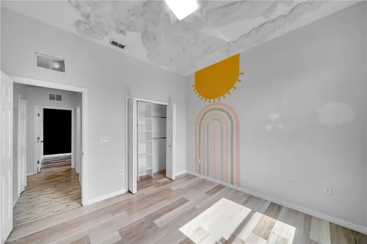 Unfurnished bedroom featuring light wood-style flooring, a closet, and baseboards