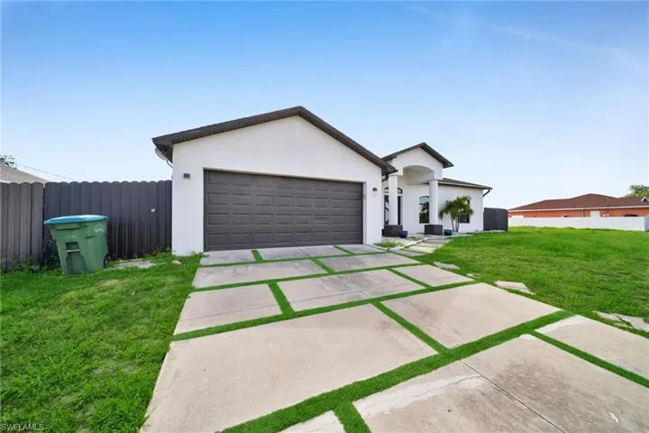 Single story home with concrete driveway, a garage, and stucco siding