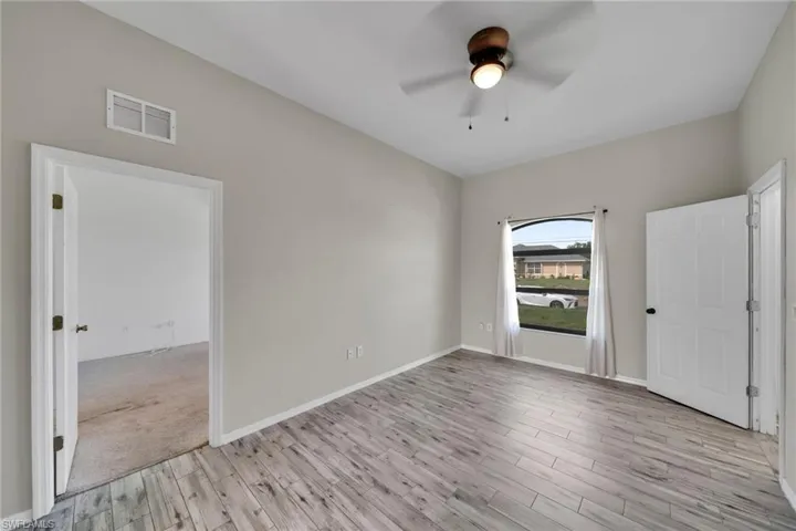 Spare room with light wood-style floors, ceiling fan, and baseboards