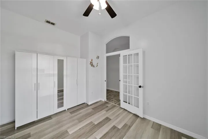 Spare room featuring french doors, light wood-type flooring, a ceiling fan, and baseboards