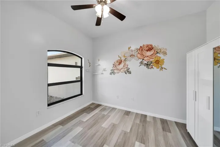 Unfurnished room with light wood-style floors, ceiling fan, and baseboards