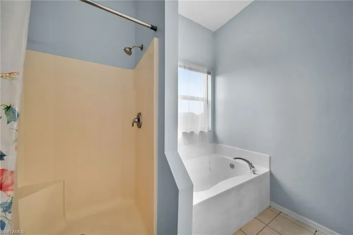 Full bath with a tile shower, a garden tub, tile patterned floors, and baseboards