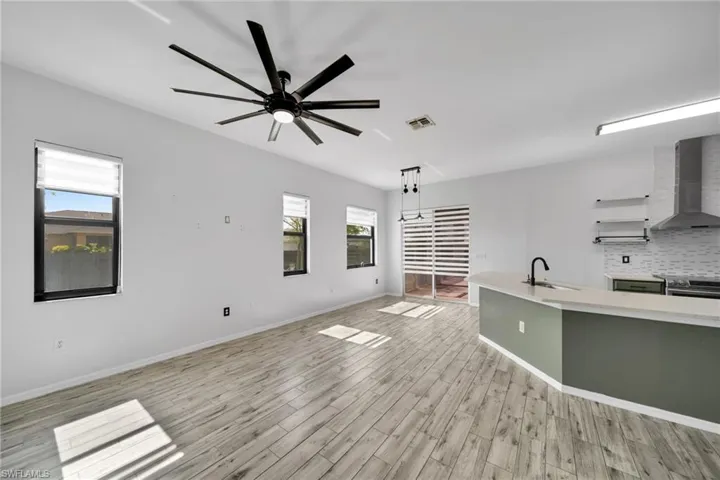 Unfurnished living room with a sink, light wood-style floors, healthy amount of natural light, and ceiling fan
