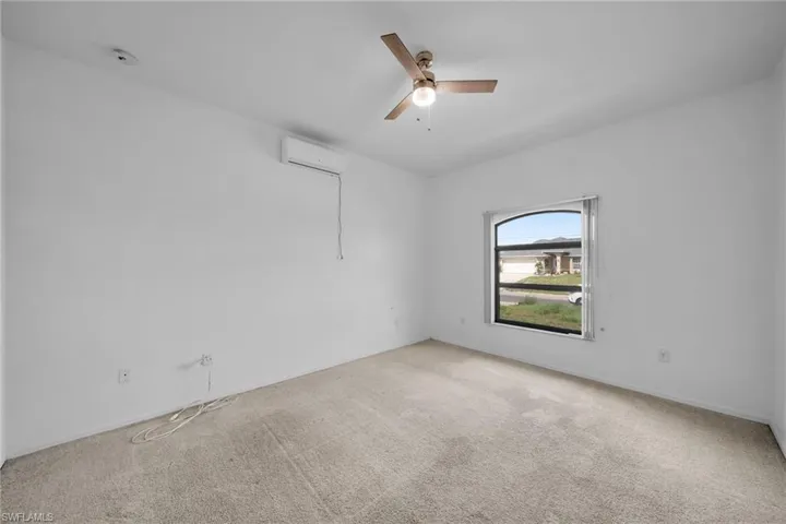 Carpeted spare room with a wall unit AC, a ceiling fan, and baseboards