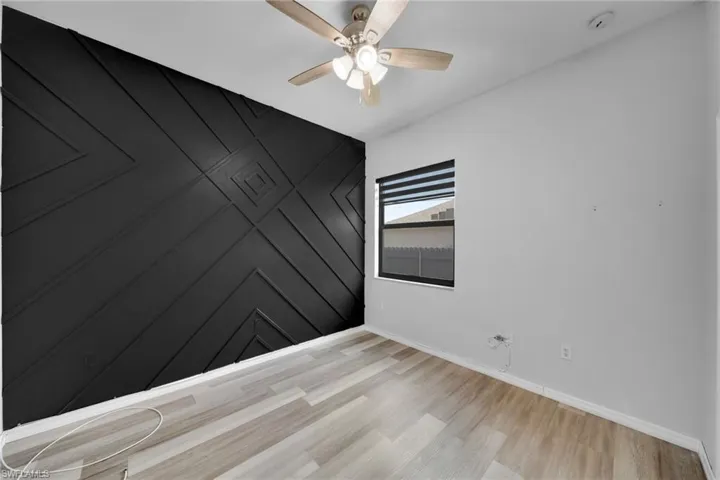 Empty room featuring baseboards, a ceiling fan, light wood finished floors, and a smoke detector