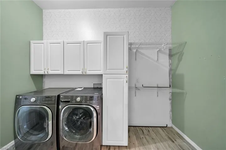 Washroom with separate washer and dryer, cabinet space, light wood-style flooring, and baseboards