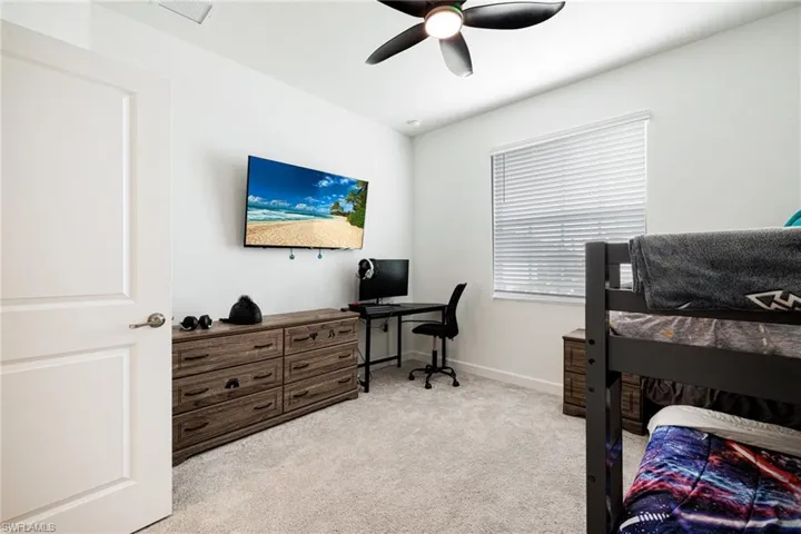 Carpeted bedroom featuring a desk and a ceiling fan