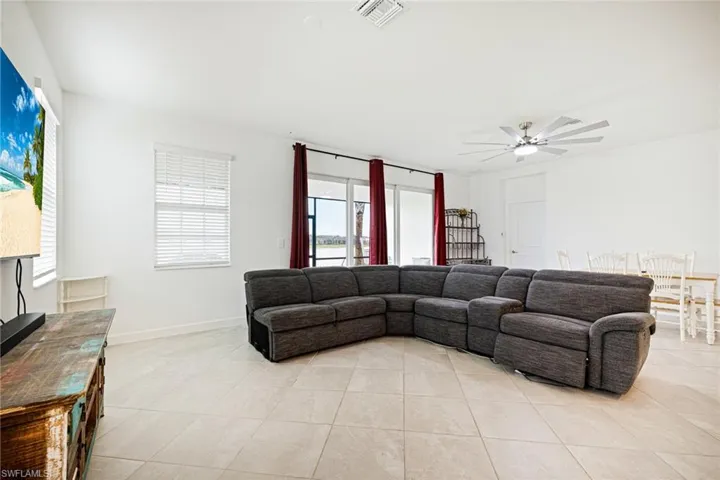 Living area with light tile patterned floors, plenty of natural light, and a ceiling fan