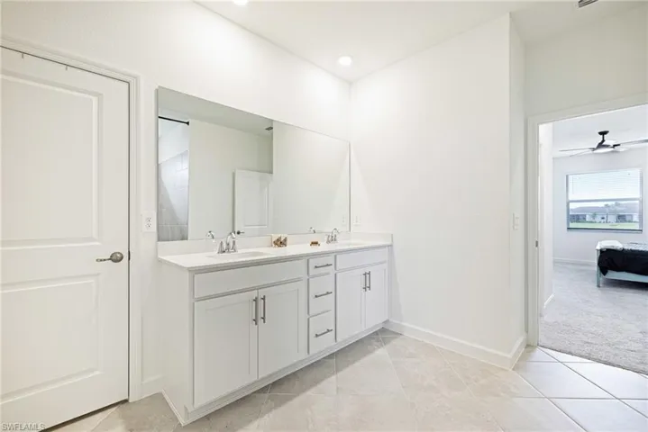 Bathroom with double vanity, tile patterned flooring, and a ceiling fan