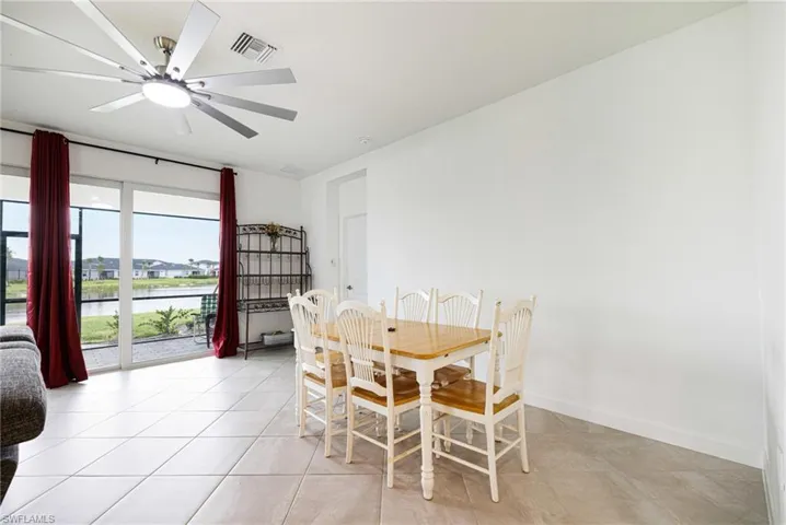 Dining room featuring a water view, light tile patterned floors, and ceiling fan