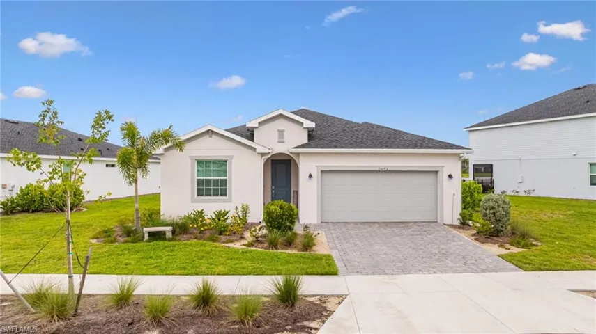 Ranch-style house featuring decorative driveway, stucco siding, an attached garage, a front yard, and a shingled roof