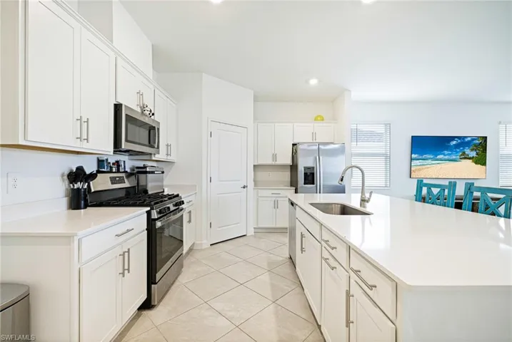Kitchen with appliances with stainless steel finishes, white cabinetry, a kitchen island with sink, light countertops, and recessed lighting