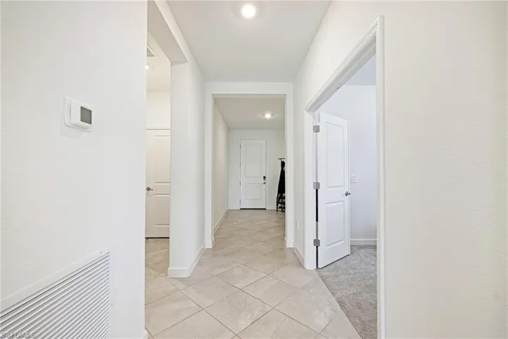 Hallway featuring light tile patterned floors and baseboards