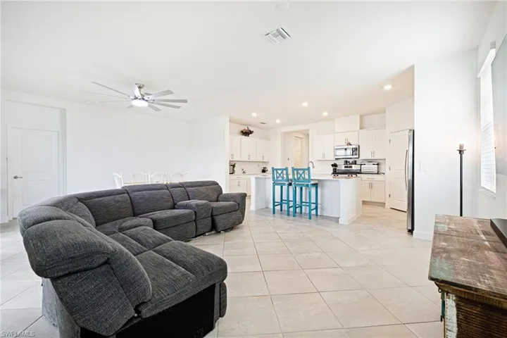 Living area with light tile patterned floors, ceiling fan, and recessed lighting