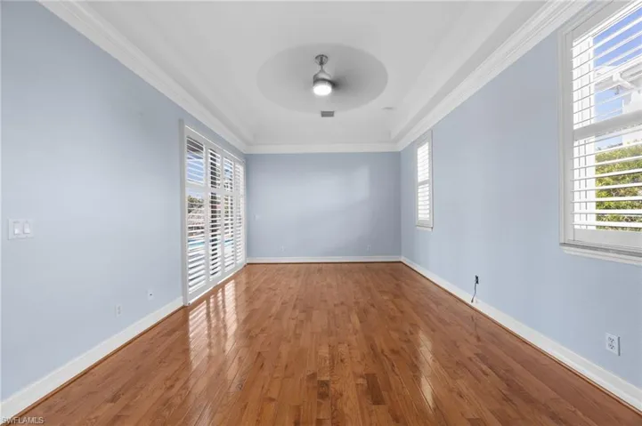 Unfurnished room featuring hardwood / wood-style flooring, ornamental molding, and a ceiling fan