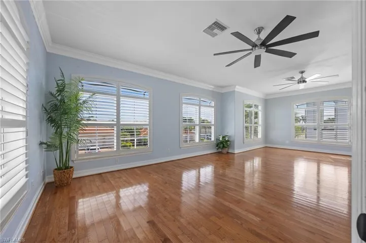 Unfurnished living room featuring ornamental molding, hardwood / wood-style floors, plenty of natural light, and a ceiling fan