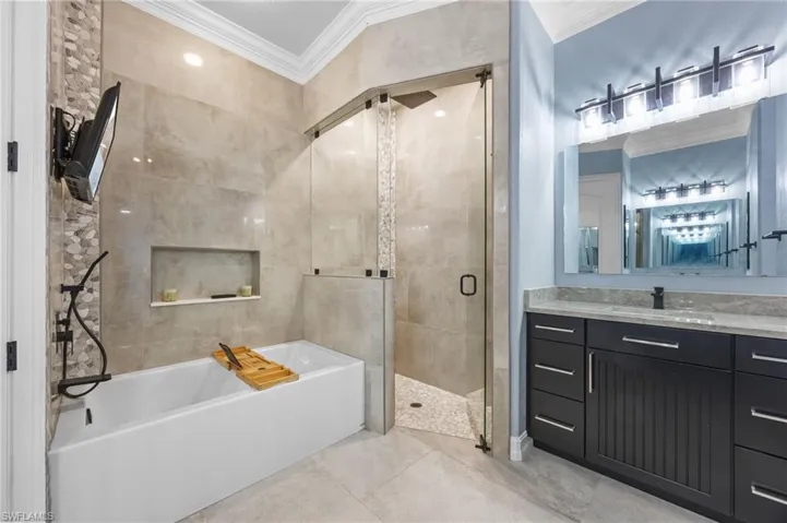 Full bath with a bath, a shower stall, ornamental molding, and vanity