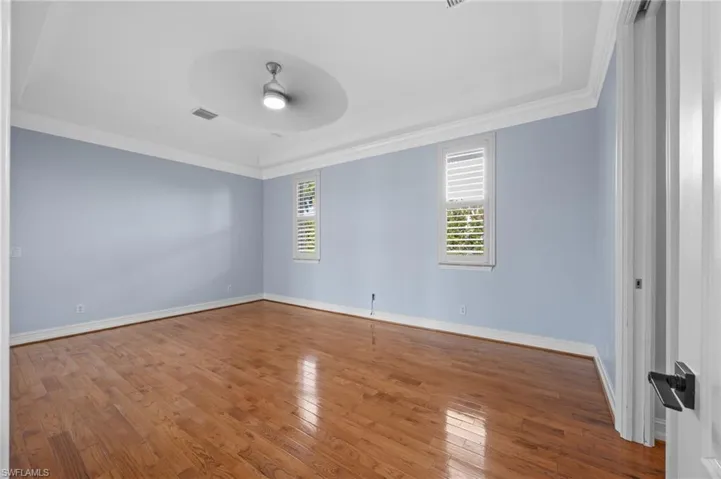 Empty room featuring hardwood / wood-style flooring, a ceiling fan, and ornamental molding