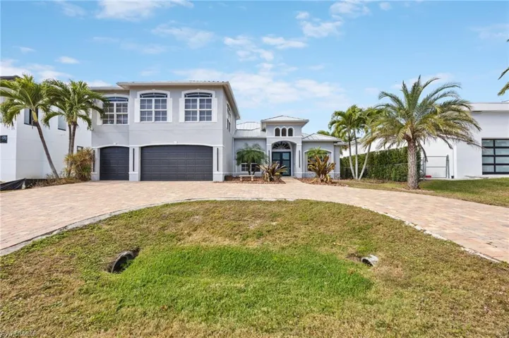 View of front of home featuring stucco siding, an attached garage, curved driveway, and a front yard