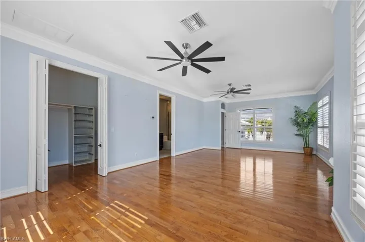 Unfurnished living room with ceiling fan, crown molding, and wood-type flooring