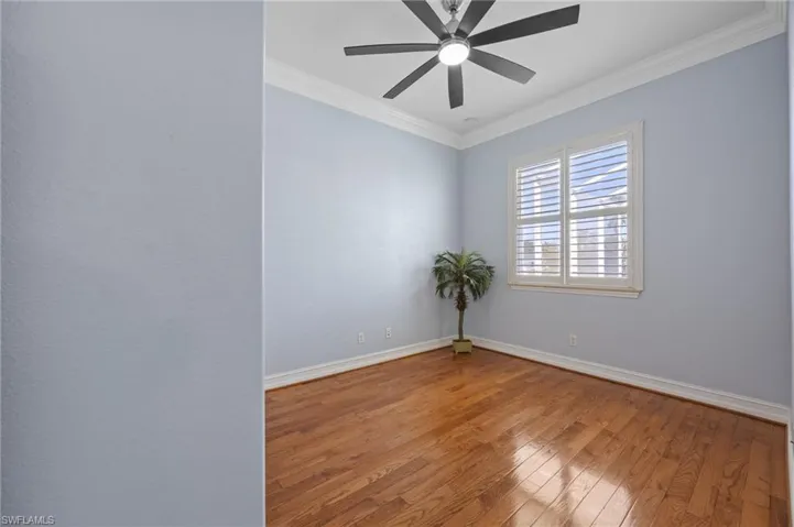 Empty room featuring ornamental molding, hardwood / wood-style flooring, and a ceiling fan
