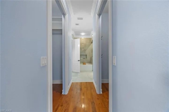 Hall with light wood-type flooring and a textured wall
