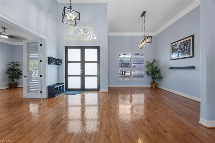 Foyer featuring french doors, ornamental molding, hardwood / wood-style flooring, a high ceiling, and suspended lighting