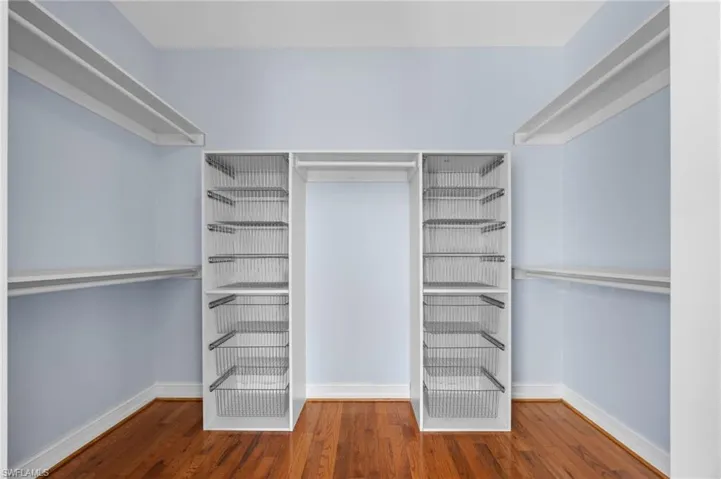 Walk in closet with dark wood-type flooring