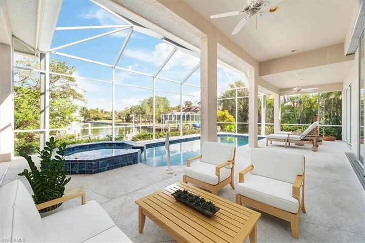 View of patio / terrace featuring ceiling fan, glass enclosure, a water view, and a swimming pool with hot tub