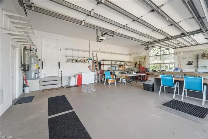 Garage featuring a garage door opener, a workshop area, and electric water heater