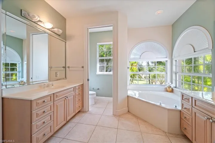 Bathroom with toilet, vanity, a tub, and tile patterned flooring
