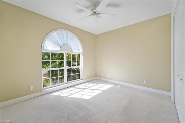 Carpeted empty room featuring ceiling fan