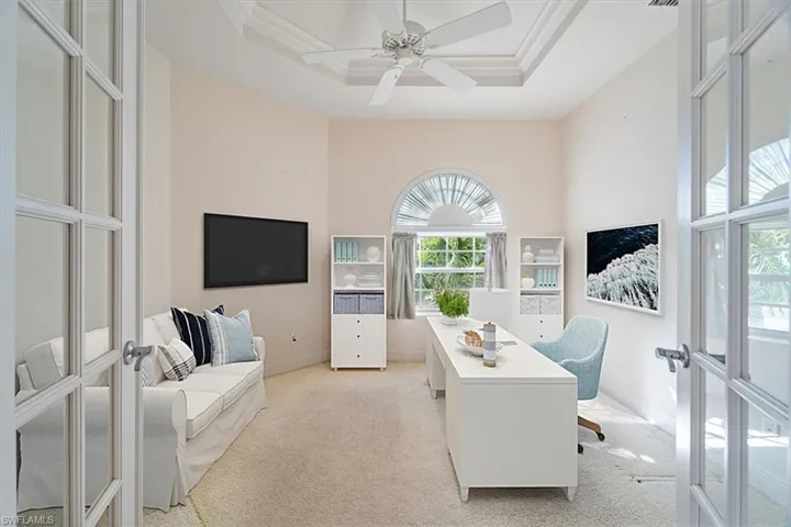 Office space featuring french doors, light carpet, and a tray ceiling
