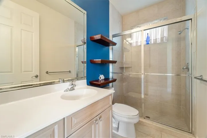 Bathroom featuring tile patterned flooring, vanity, toilet, and a shower with door