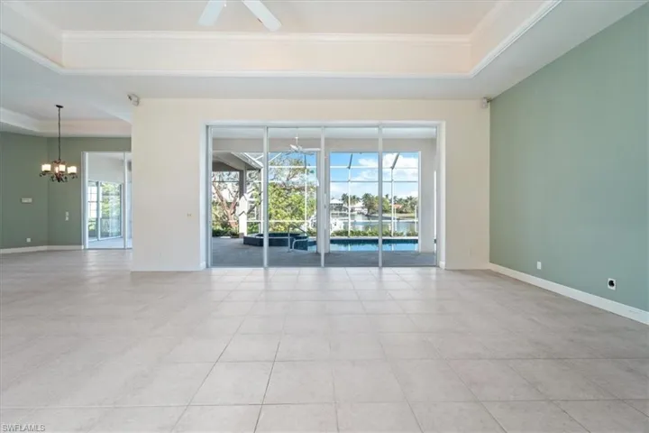 Unfurnished room featuring ornamental molding, ceiling fan with notable chandelier, a healthy amount of sunlight, and a raised ceiling