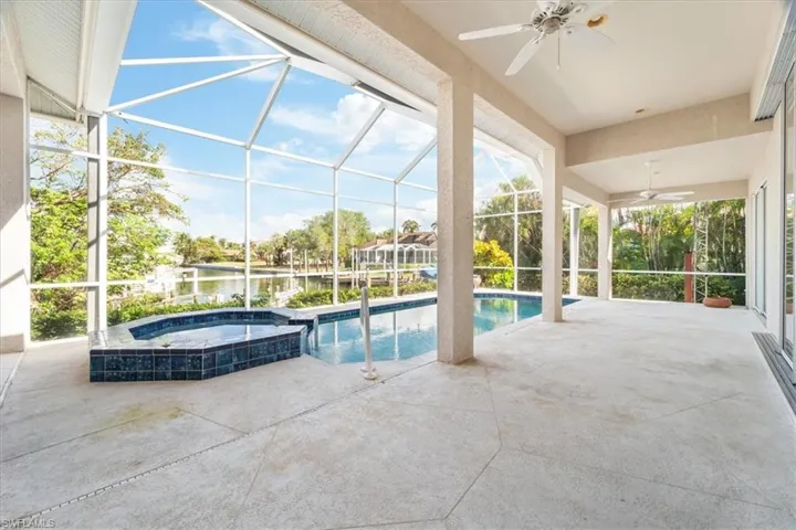 View of swimming pool featuring an in ground hot tub, a patio, a water view, a lanai, and ceiling fan