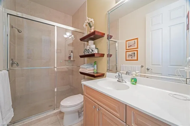 Bathroom with walk in shower, tile patterned flooring, vanity, and toilet
