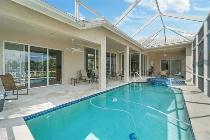 View of swimming pool featuring ceiling fan, an in ground hot tub, a lanai, and a patio area