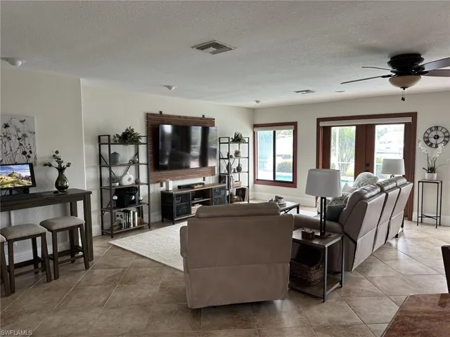 Living area featuring a textured ceiling, ceiling fan, and light tile patterned floors