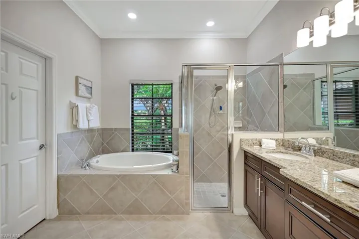 Full bath featuring double vanity, a bath, crown molding, a stall shower, and tile patterned flooring