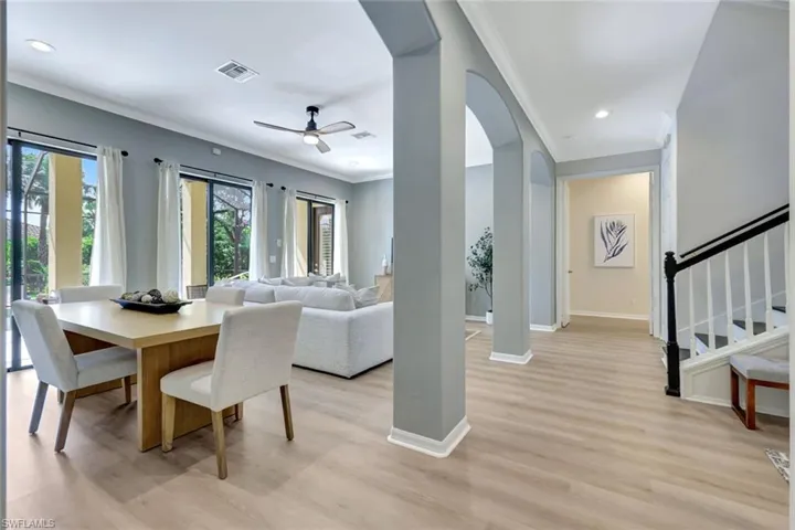 Dining area with arched walkways, crown molding, light wood-type flooring, a ceiling fan, and recessed lighting