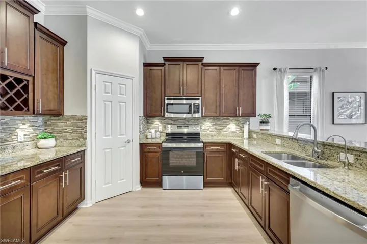 Kitchen featuring appliances with stainless steel finishes, ornamental molding, light wood-style floors, tasteful backsplash, and recessed lighting