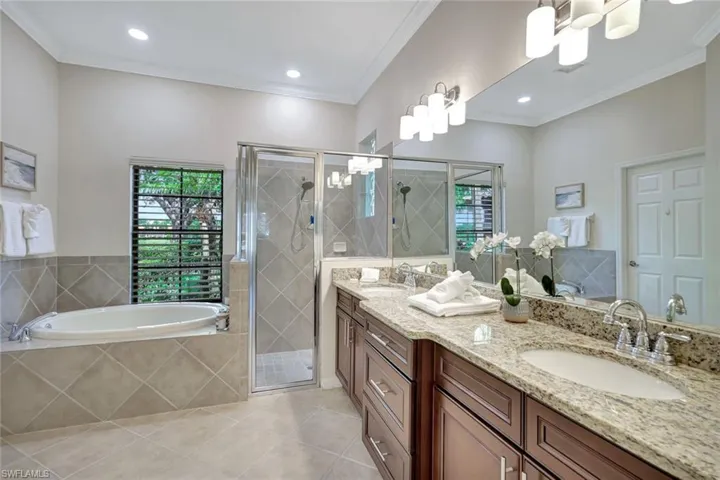 Full bath featuring ornamental molding, double vanity, a bath, healthy amount of natural light, and tile patterned floors