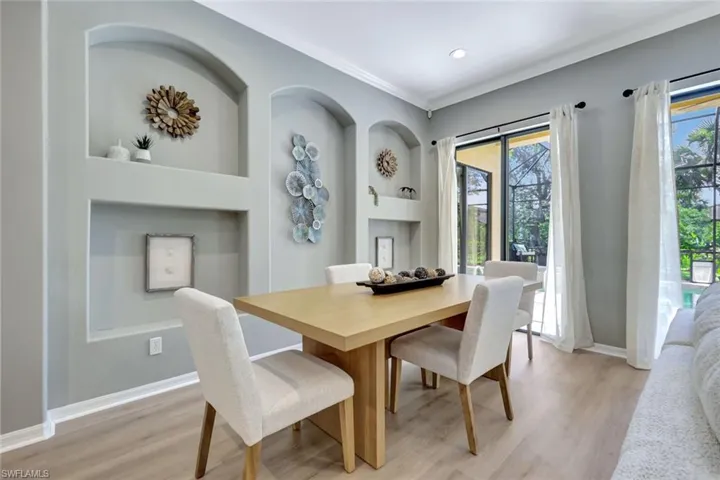 Dining room with light wood finished floors, ornamental molding, and built in features