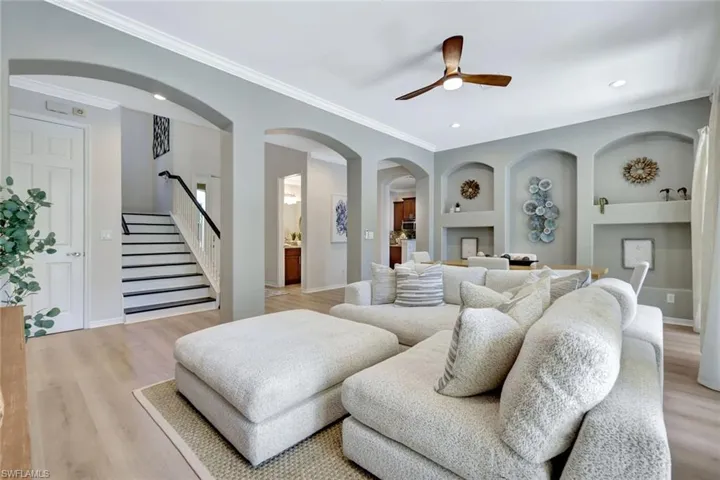 Living room with light wood-style floors, crown molding, recessed lighting, stairs, and a ceiling fan