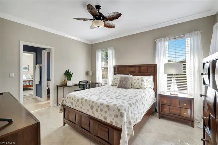 Bedroom featuring crown molding, light tile patterned floors, and a ceiling fan