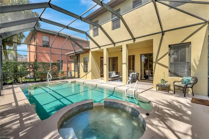 Rear view of house with stucco siding, a pool with connected hot tub, and a patio area