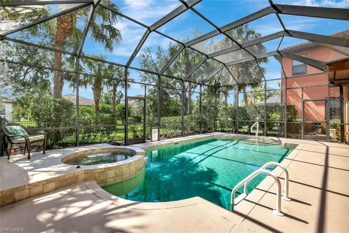 View of pool with a pool with connected hot tub, a patio area, and enclosure