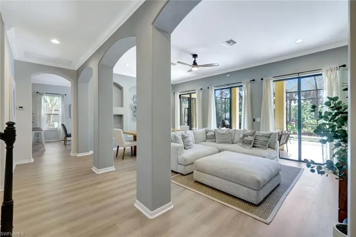 Living area featuring light wood-style floors, crown molding, recessed lighting, arched walkways, and ceiling fan